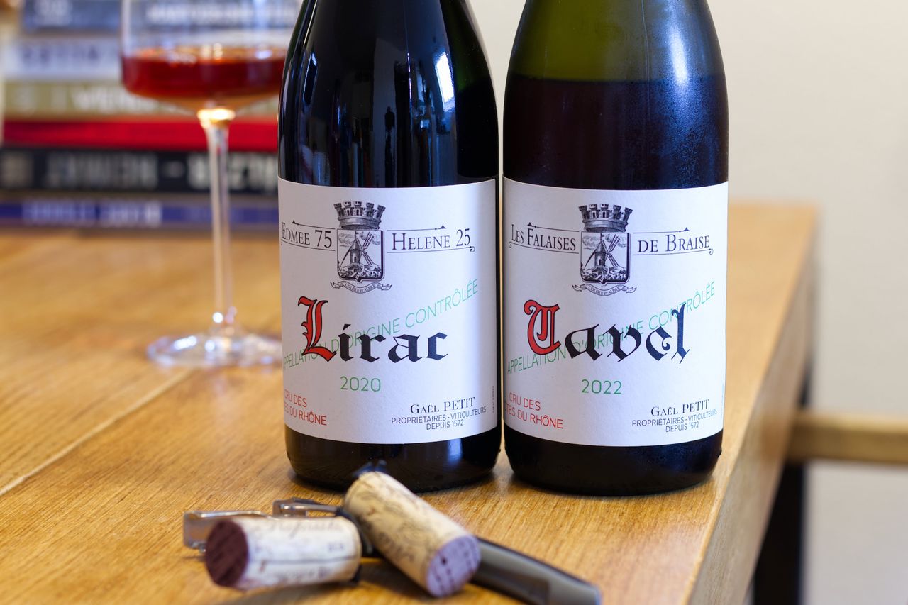 Two bottles of wine from the Seehaldenhof winery stand on a wooden table. Behind them are a wine glass and a stack of books.